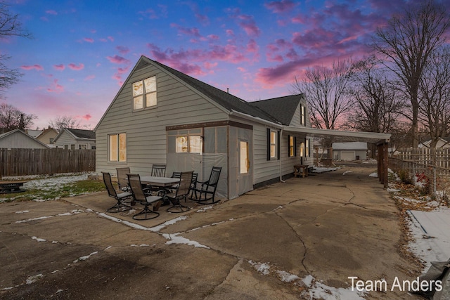 back house at dusk featuring a carport