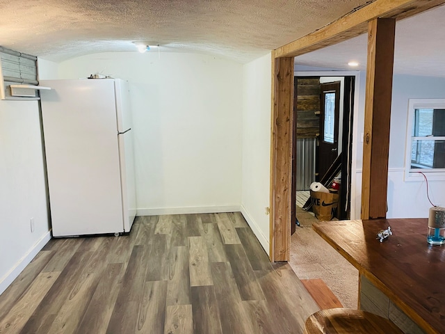 corridor with lofted ceiling, wood-type flooring, and a textured ceiling