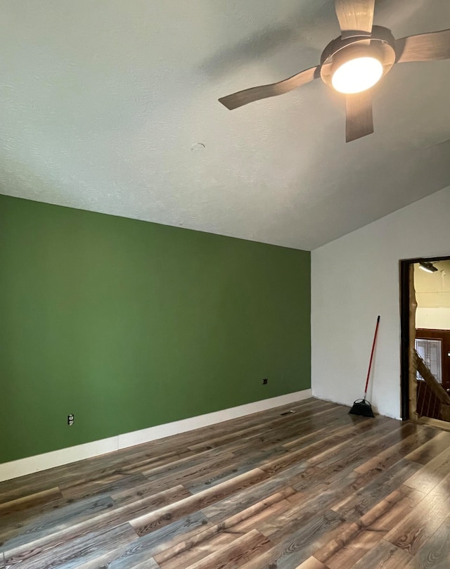 spare room with a textured ceiling, ceiling fan, dark wood-type flooring, and vaulted ceiling