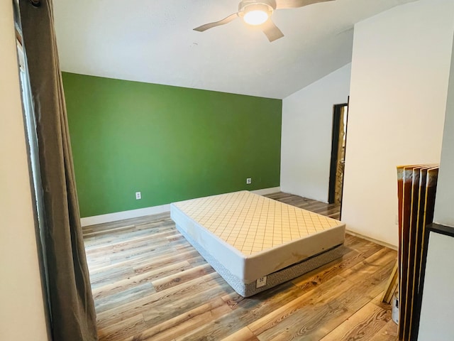 bedroom with ceiling fan, lofted ceiling, and light wood-type flooring