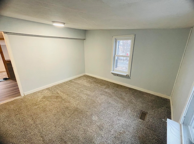 carpeted empty room with vaulted ceiling and a textured ceiling