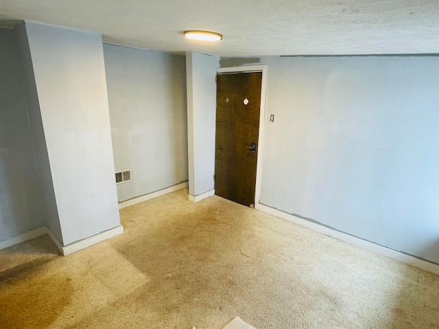 spare room with light carpet and a textured ceiling