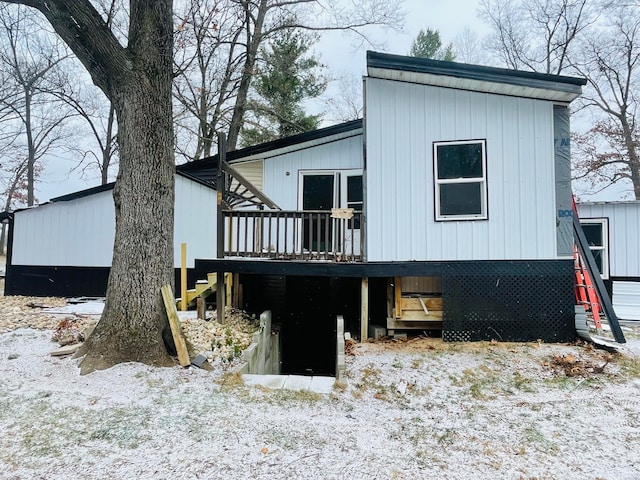 snow covered back of property with a deck