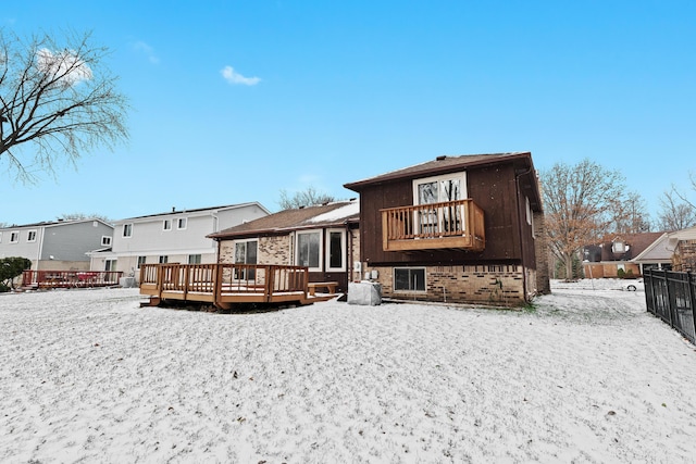 snow covered property with a balcony and a deck