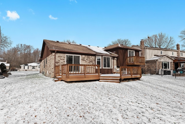 snow covered rear of property with a wooden deck