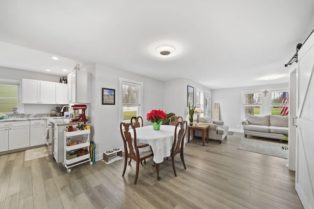 dining area featuring a barn door, a healthy amount of sunlight, and light hardwood / wood-style floors