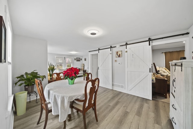 dining area featuring light wood-type flooring and a barn door