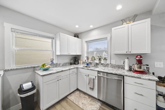 kitchen featuring light wood-type flooring, light stone counters, sink, dishwasher, and white cabinetry