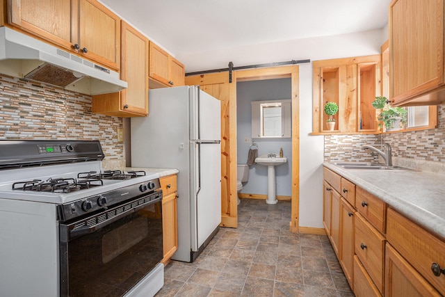 kitchen featuring white appliances, sink, a barn door, light brown cabinetry, and tasteful backsplash