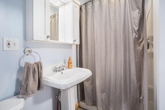 bathroom featuring walk in shower, sink, and toilet