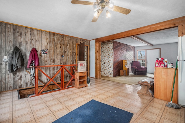 interior space featuring ceiling fan and wooden walls