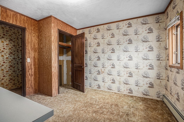 unfurnished room with a textured ceiling, carpet floors, a baseboard radiator, and crown molding