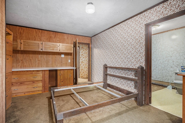 bedroom featuring carpet flooring, a textured ceiling, ornamental molding, and wood walls