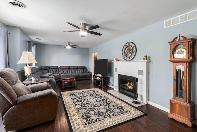 living room featuring ceiling fan, dark hardwood / wood-style floors, and a brick fireplace