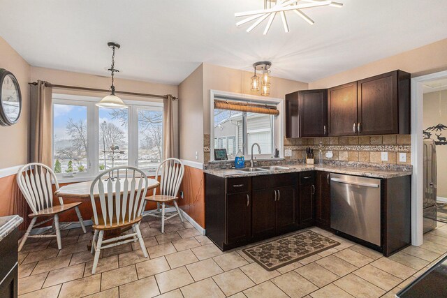 kitchen featuring backsplash, stainless steel dishwasher, sink, a chandelier, and hanging light fixtures