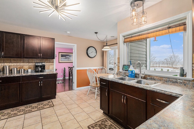 kitchen featuring sink, hanging light fixtures, an inviting chandelier, backsplash, and light tile patterned floors