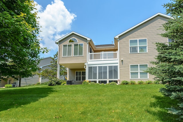 back of property with central air condition unit, a balcony, and a lawn