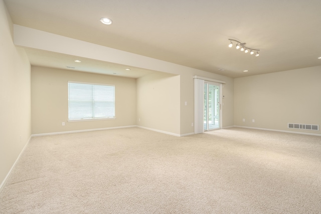 spare room with light colored carpet, rail lighting, and a wealth of natural light