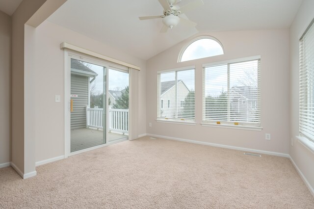 spare room featuring plenty of natural light, light colored carpet, and vaulted ceiling