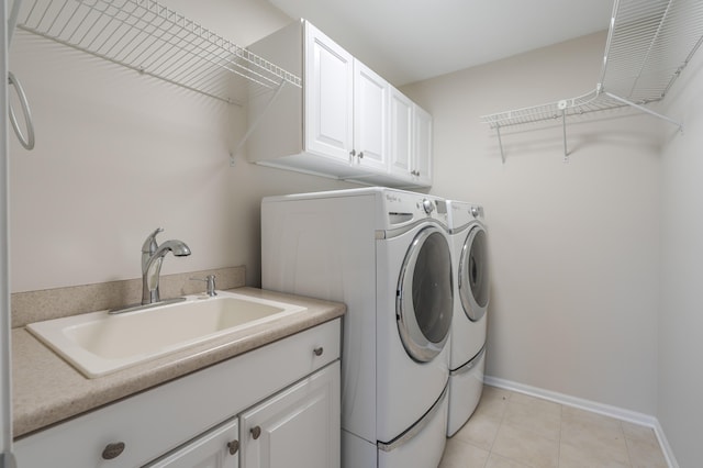 laundry area featuring washer and dryer, light tile patterned flooring, cabinets, and sink