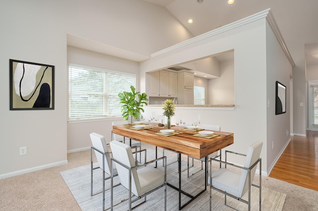 dining space with light carpet and high vaulted ceiling