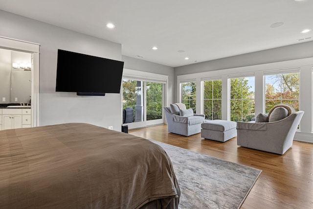 bedroom featuring a sink, ensuite bath, wood finished floors, and recessed lighting