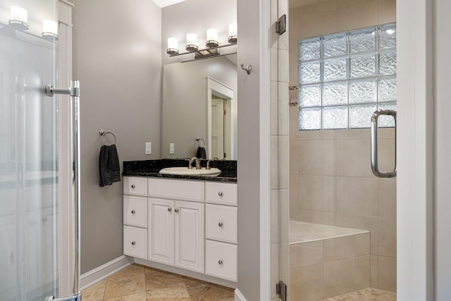 full bath with stone finish floor, a stall shower, baseboards, and vanity