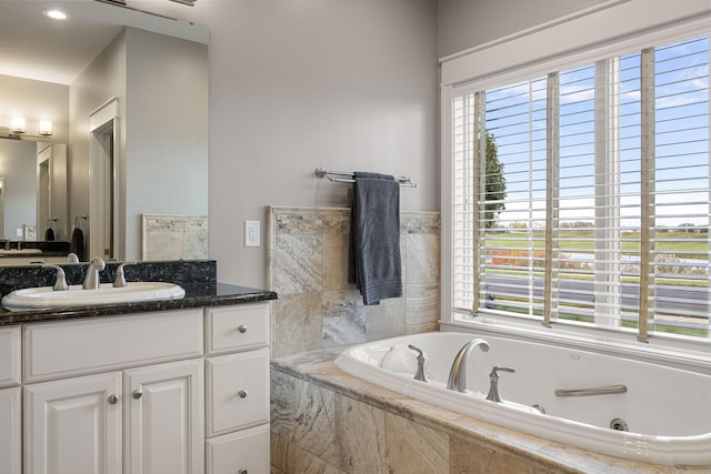 full bath featuring a jetted tub, plenty of natural light, and vanity