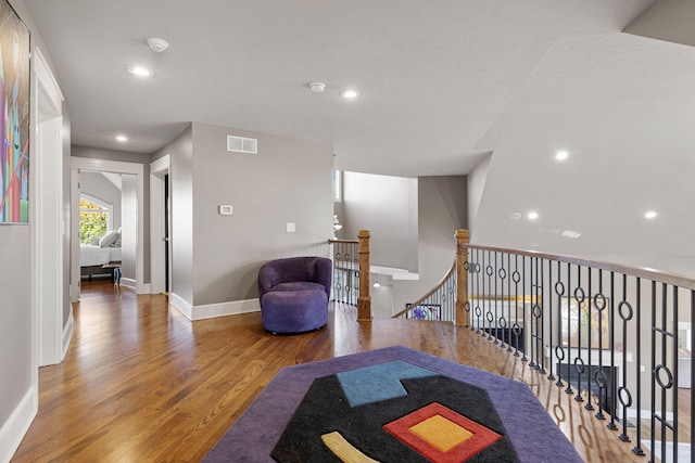 living area featuring recessed lighting, visible vents, an upstairs landing, wood finished floors, and baseboards