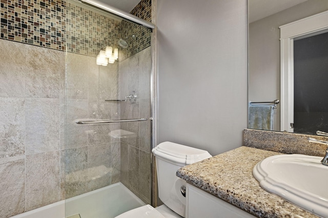 bathroom with a tile shower, vanity, and toilet