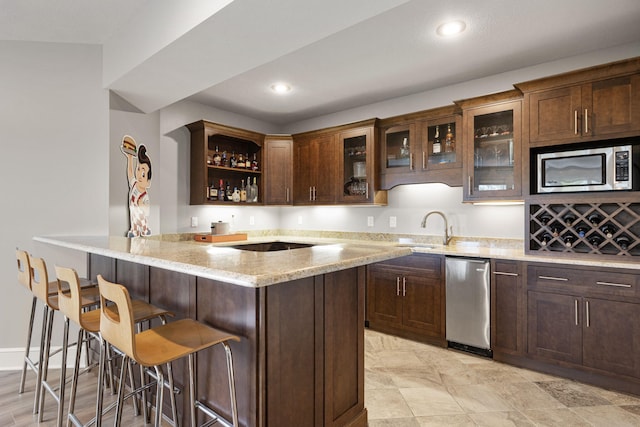 bar with recessed lighting, stainless steel microwave, a sink, wet bar, and baseboards