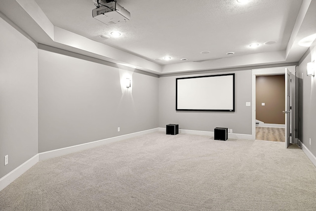 cinema room with a textured ceiling, recessed lighting, carpet flooring, baseboards, and a tray ceiling