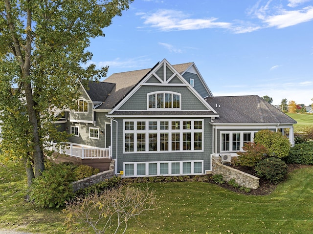 back of property featuring a shingled roof and a yard