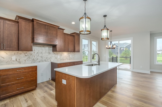 kitchen with light wood-type flooring, a center island with sink, a wealth of natural light, and sink