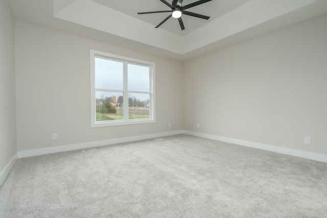 carpeted spare room featuring ceiling fan and a raised ceiling