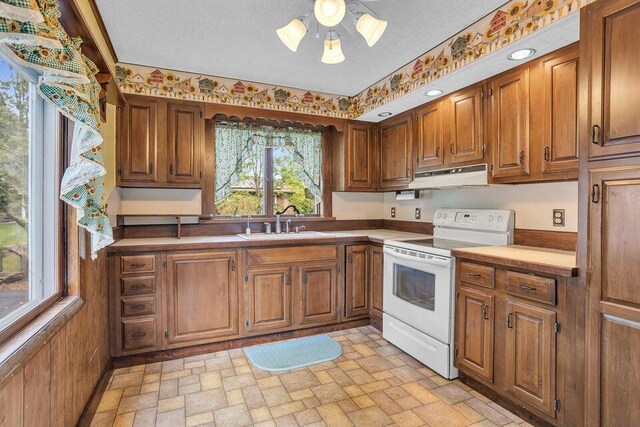 kitchen featuring a textured ceiling, white electric stove, and sink