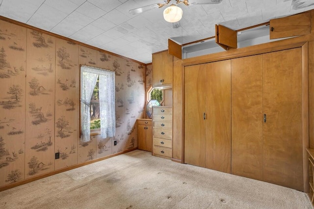 unfurnished bedroom featuring ceiling fan, crown molding, and light colored carpet