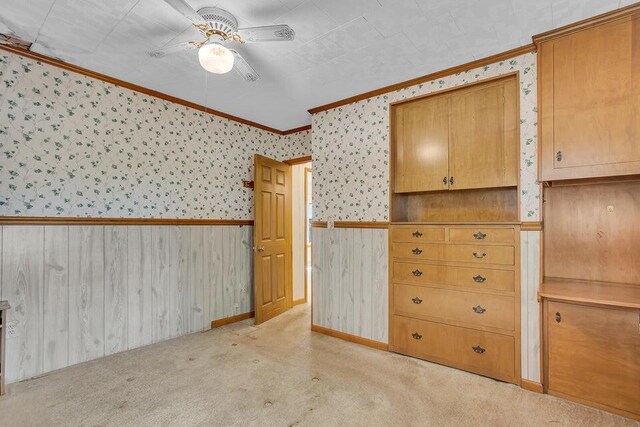 spare room featuring ceiling fan, ornamental molding, and light carpet