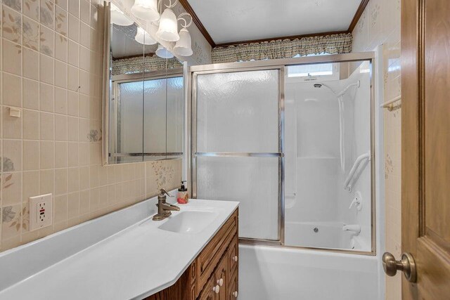 bathroom with shower / bath combination with glass door, vanity, tasteful backsplash, and tile walls