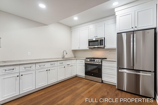 kitchen with white cabinetry, dark wood-type flooring, stainless steel appliances, and sink