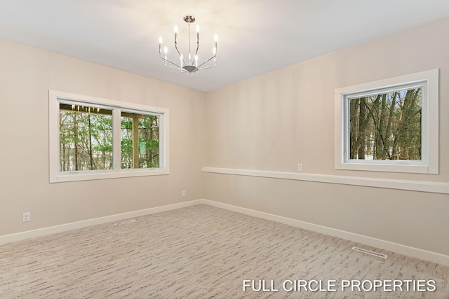 carpeted empty room featuring a notable chandelier and plenty of natural light