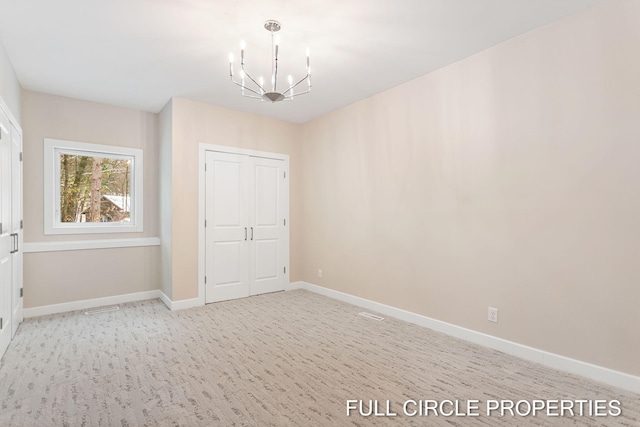 unfurnished room featuring light colored carpet and a chandelier