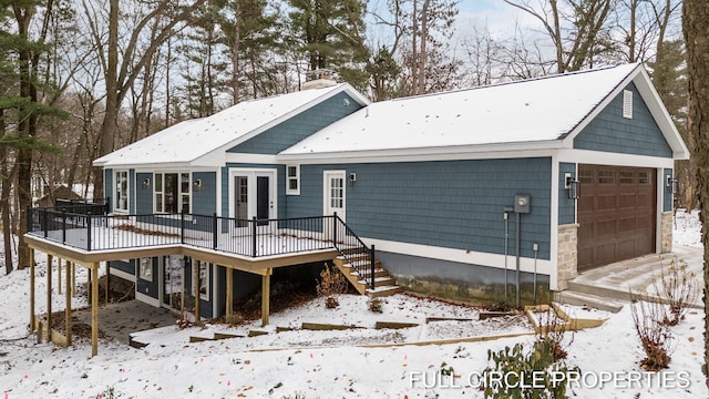 snow covered property with a deck and a garage