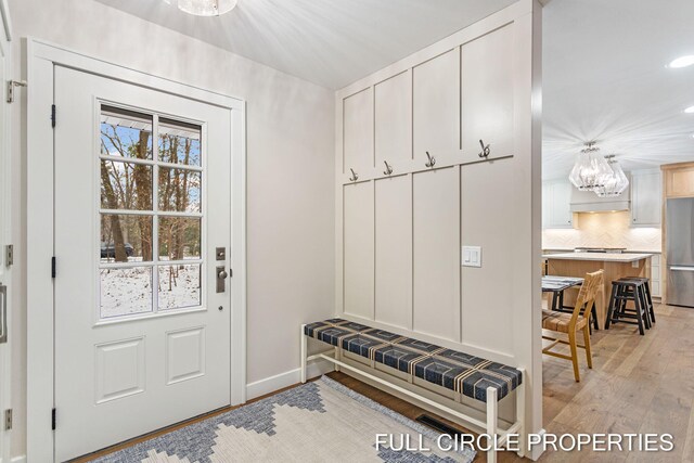 mudroom with a chandelier and light wood-type flooring