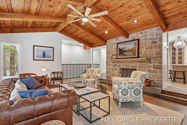 living room with ceiling fan, lofted ceiling with beams, light hardwood / wood-style flooring, wooden ceiling, and a stone fireplace