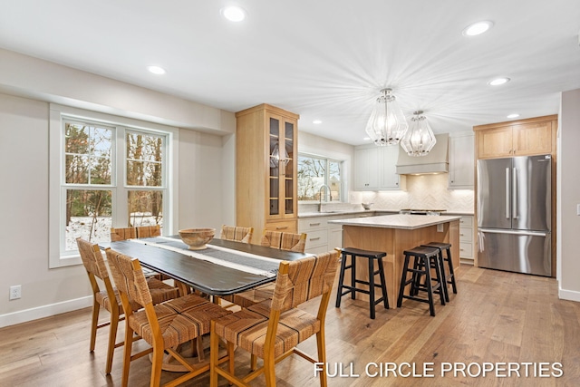 dining space featuring an inviting chandelier, light hardwood / wood-style flooring, a healthy amount of sunlight, and sink