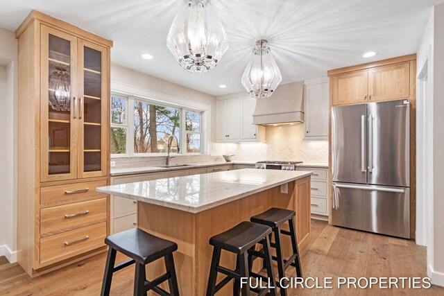 kitchen featuring a center island, premium range hood, sink, light hardwood / wood-style flooring, and appliances with stainless steel finishes