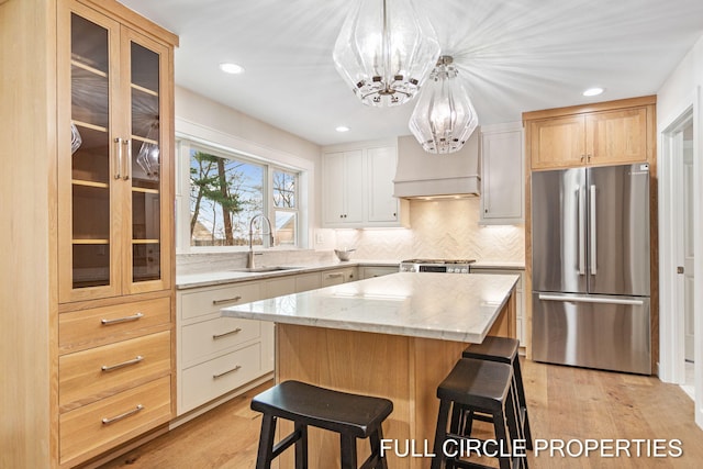 kitchen featuring sink, stainless steel appliances, a kitchen island, white cabinets, and custom exhaust hood