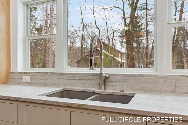 kitchen with light stone counters, a healthy amount of sunlight, and sink