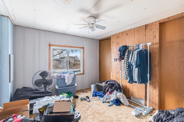 misc room with carpet floors, ceiling fan, and wooden walls